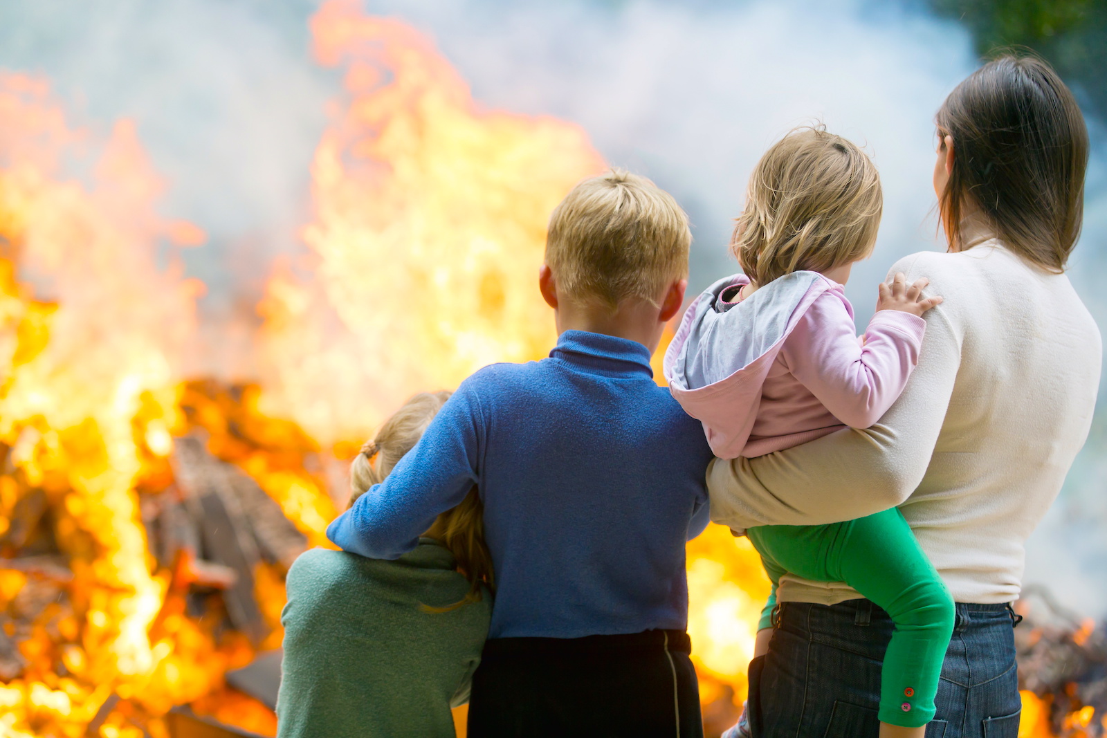 mother and her three young children watch their house burn from a safe distance