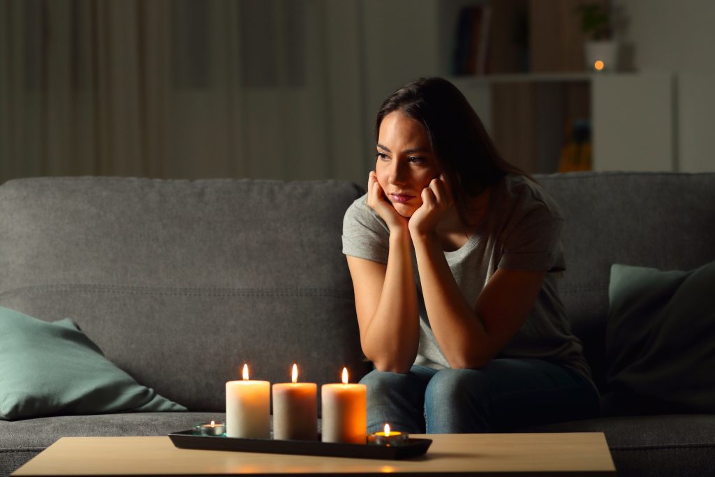 Young woman sitting next to candle light in a house without electricity
