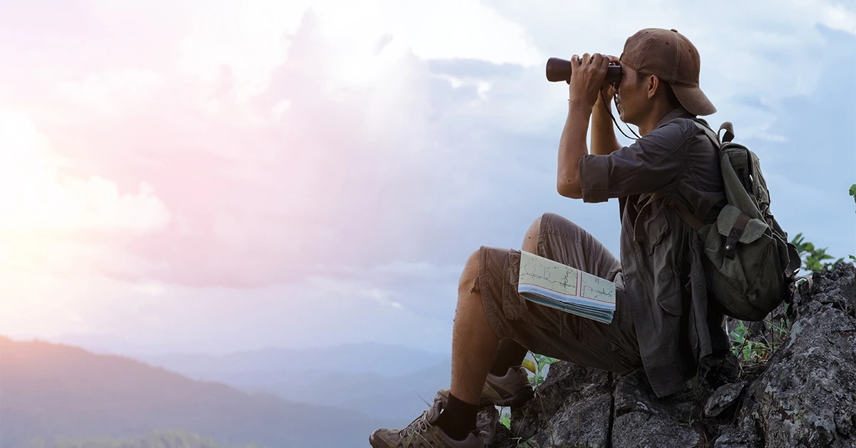 man using binoculars surviving in the wild with bushcraft skills