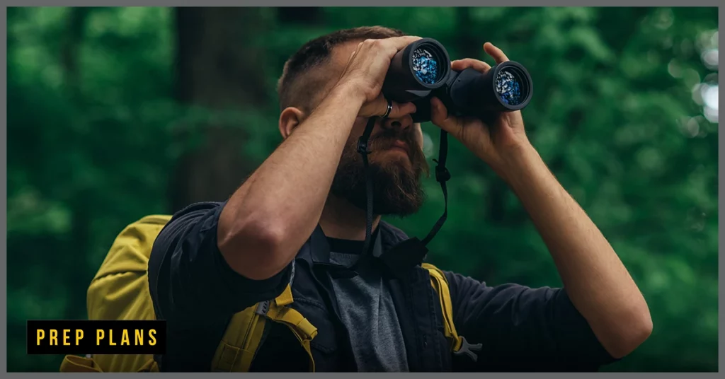 man using binoculars to survive in the woods