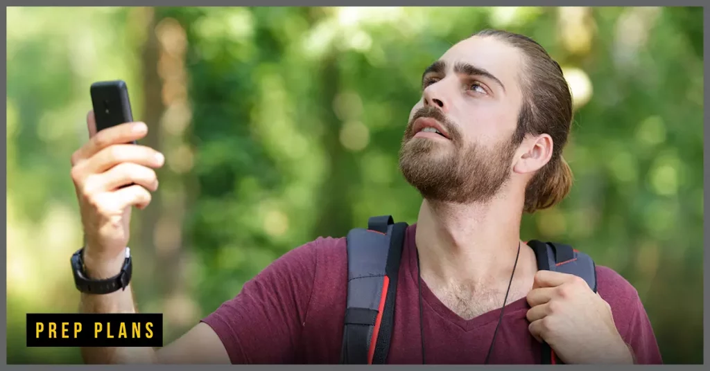 man using a gps locator to find help in the forest