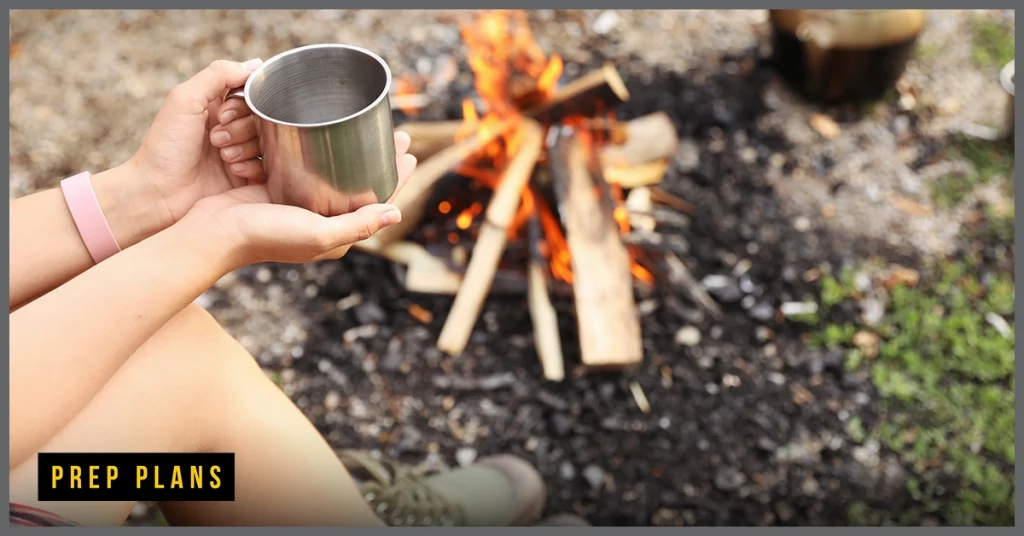 person sitting with a drink near a camp fire