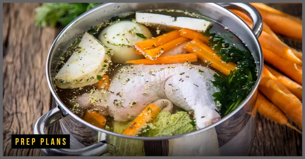 raw uncooked chicken leg and thigh floating in a stock pot with vegetables